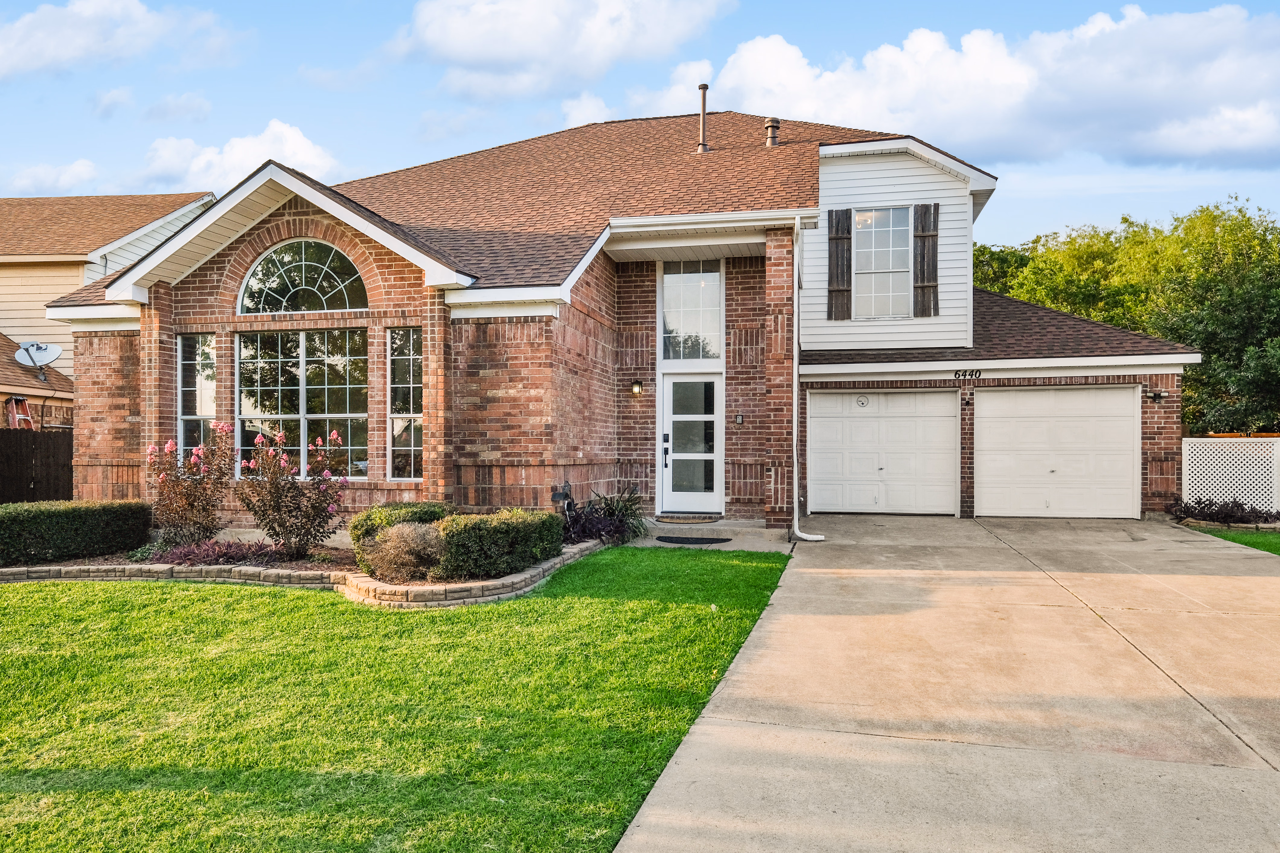 Front of house — brick exterior, arched window, driveway.