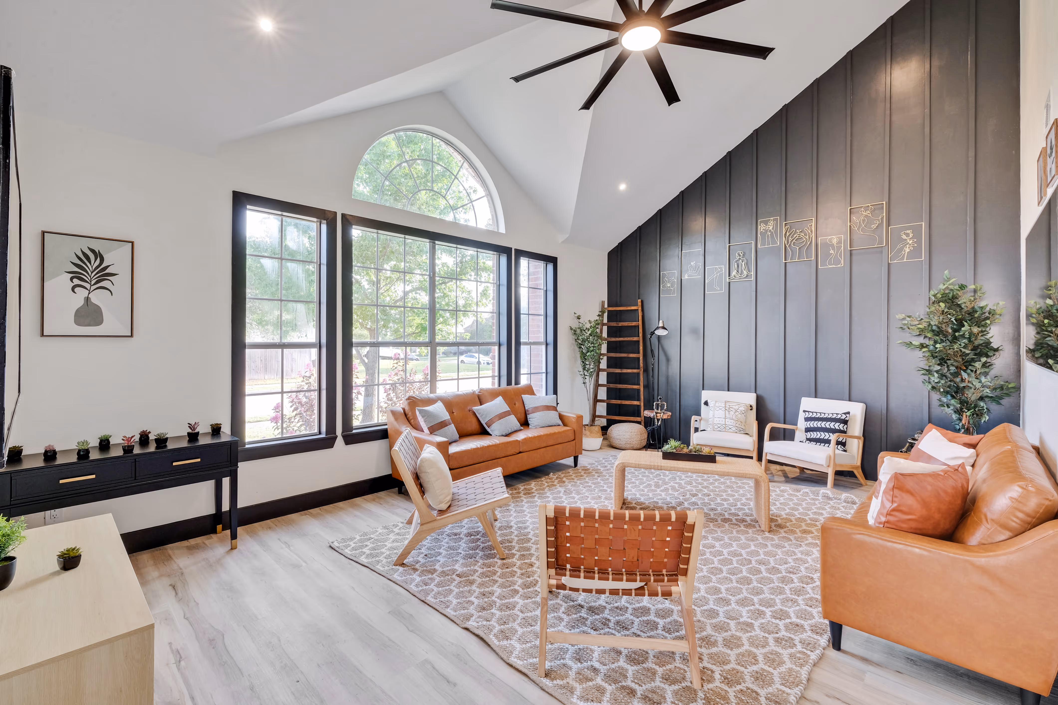 Living room — vaulted ceiling, arched window, leather sofas.