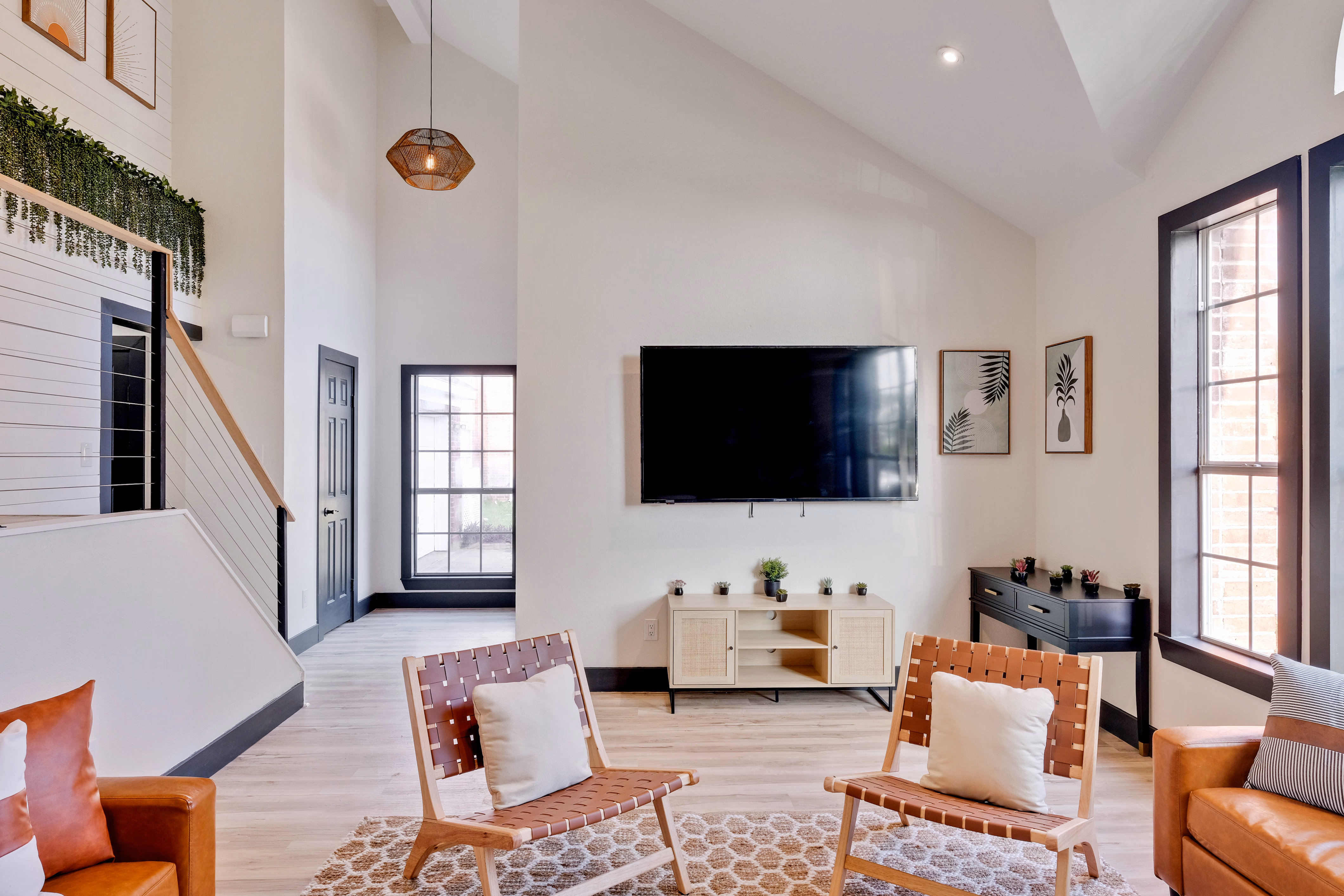 Living room — TV wall with woven leather chairs and console.