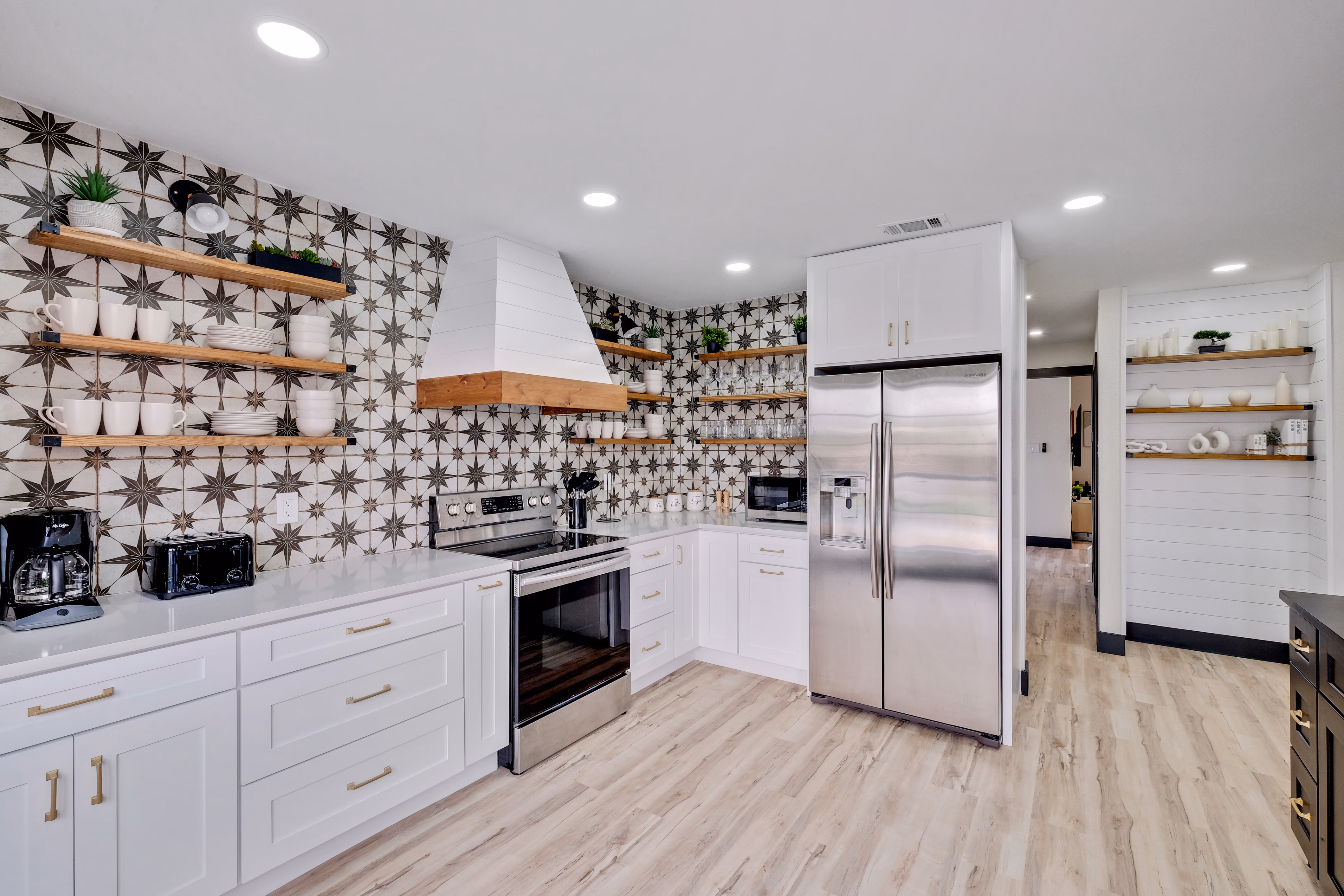 Kitchen — patterned star backsplash, range hood, stainless fridge.
