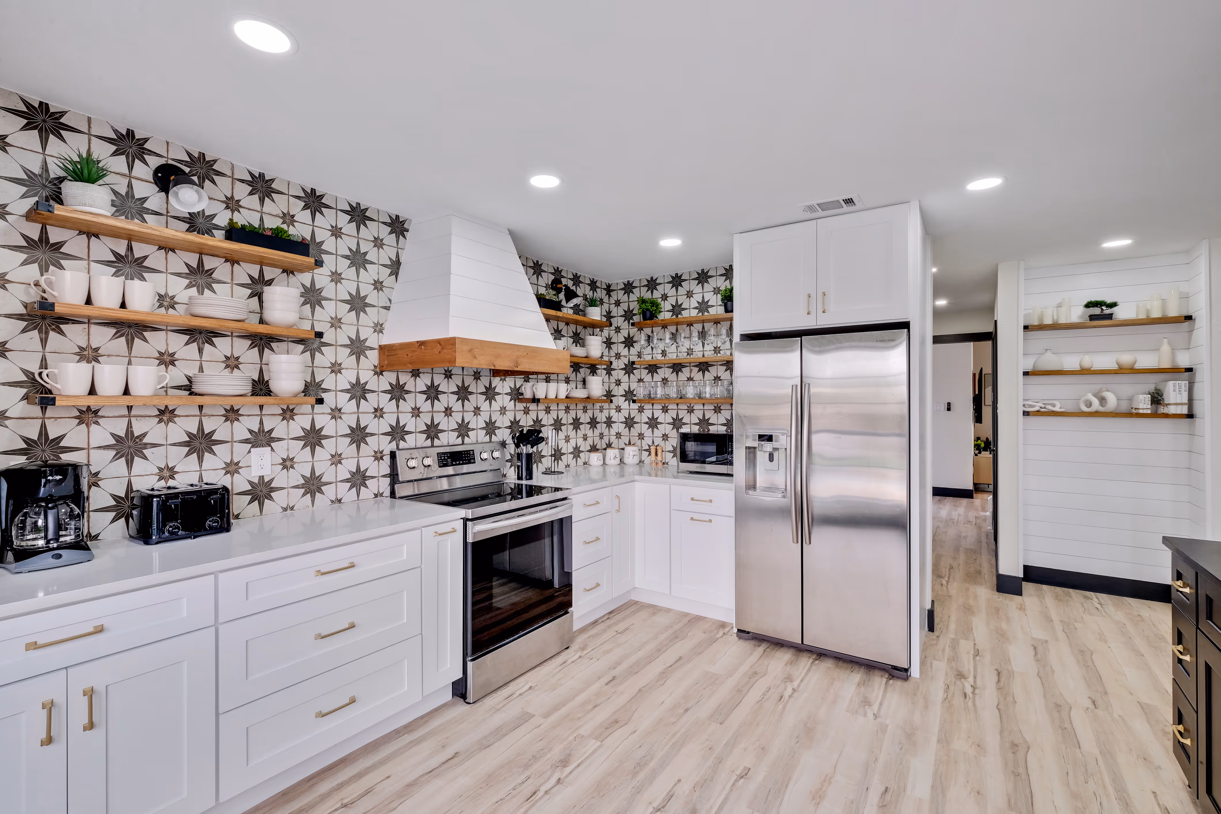 Kitchen — patterned star backsplash, range hood, stainless fridge.