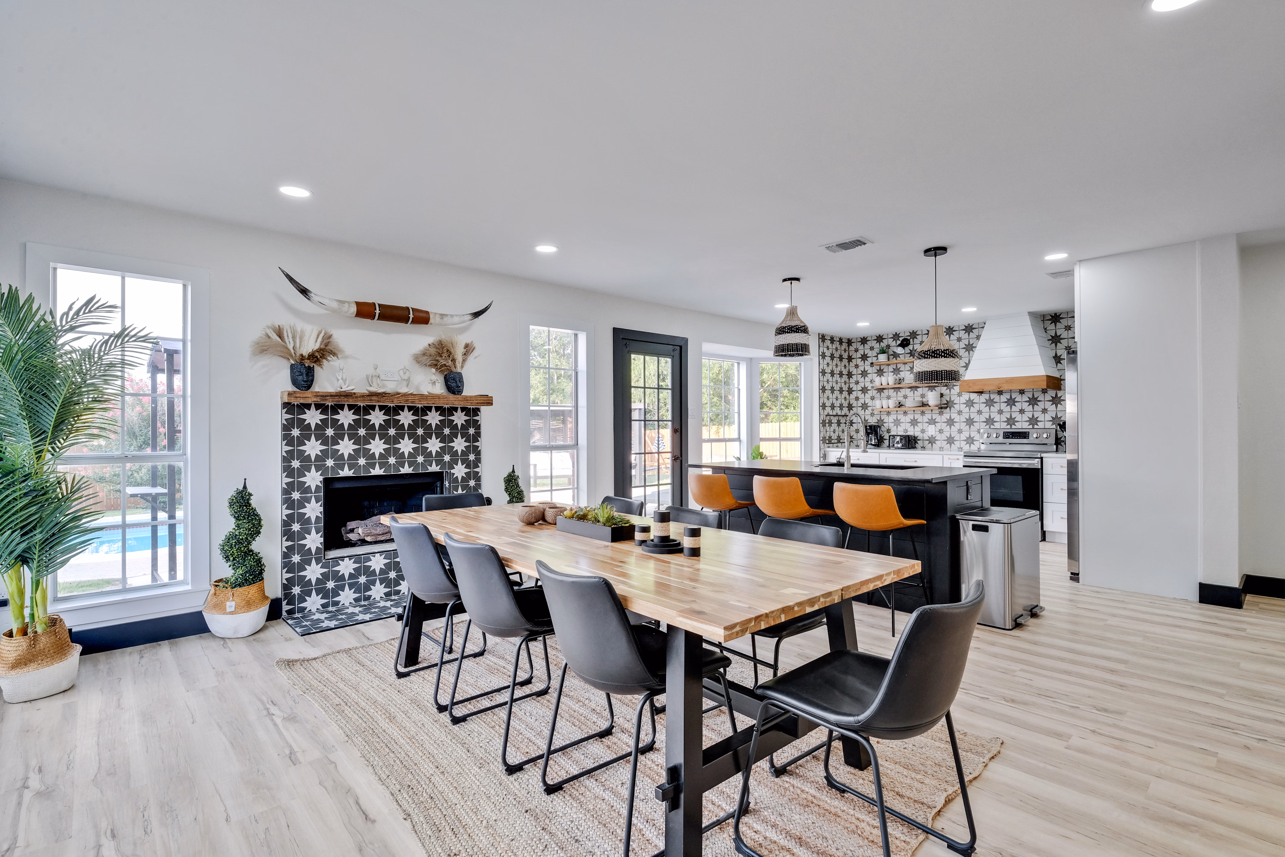 Dining and kitchen with fireplace and pool view through windows.