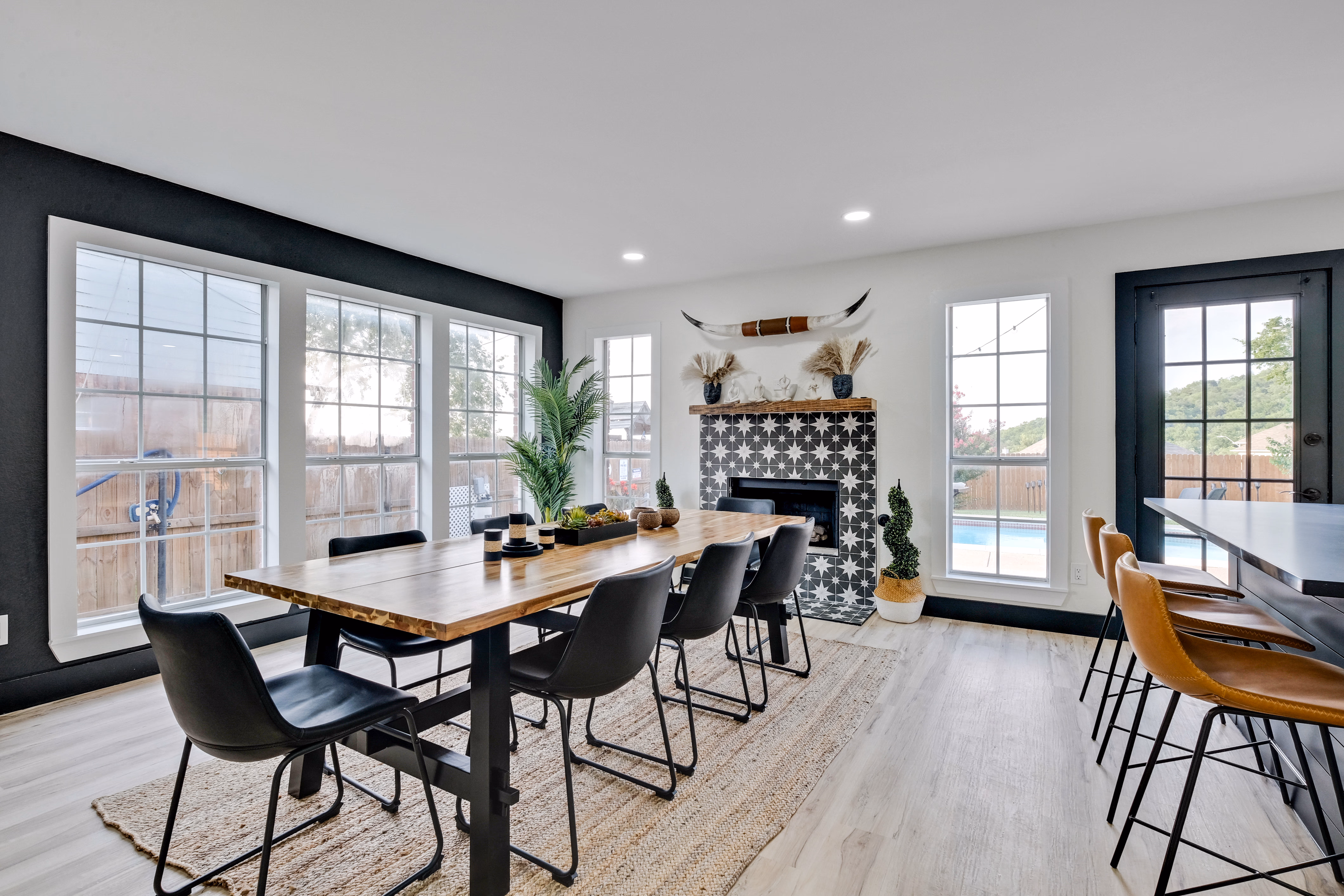 Dining room — black accent wall, large windows, fireplace.