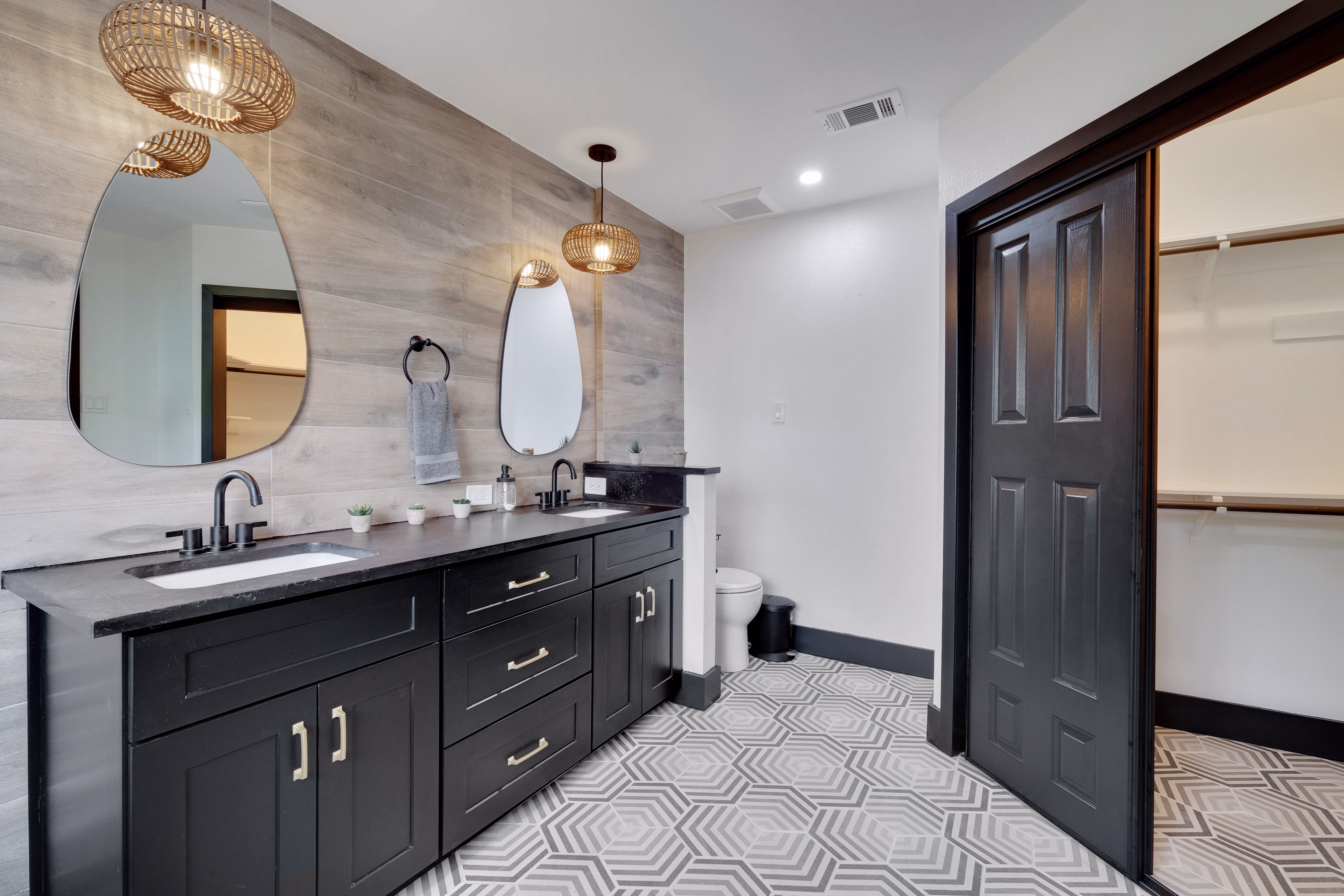 Upstairs hall bath — dual vanity, geometric tile floor, walk-in closet.