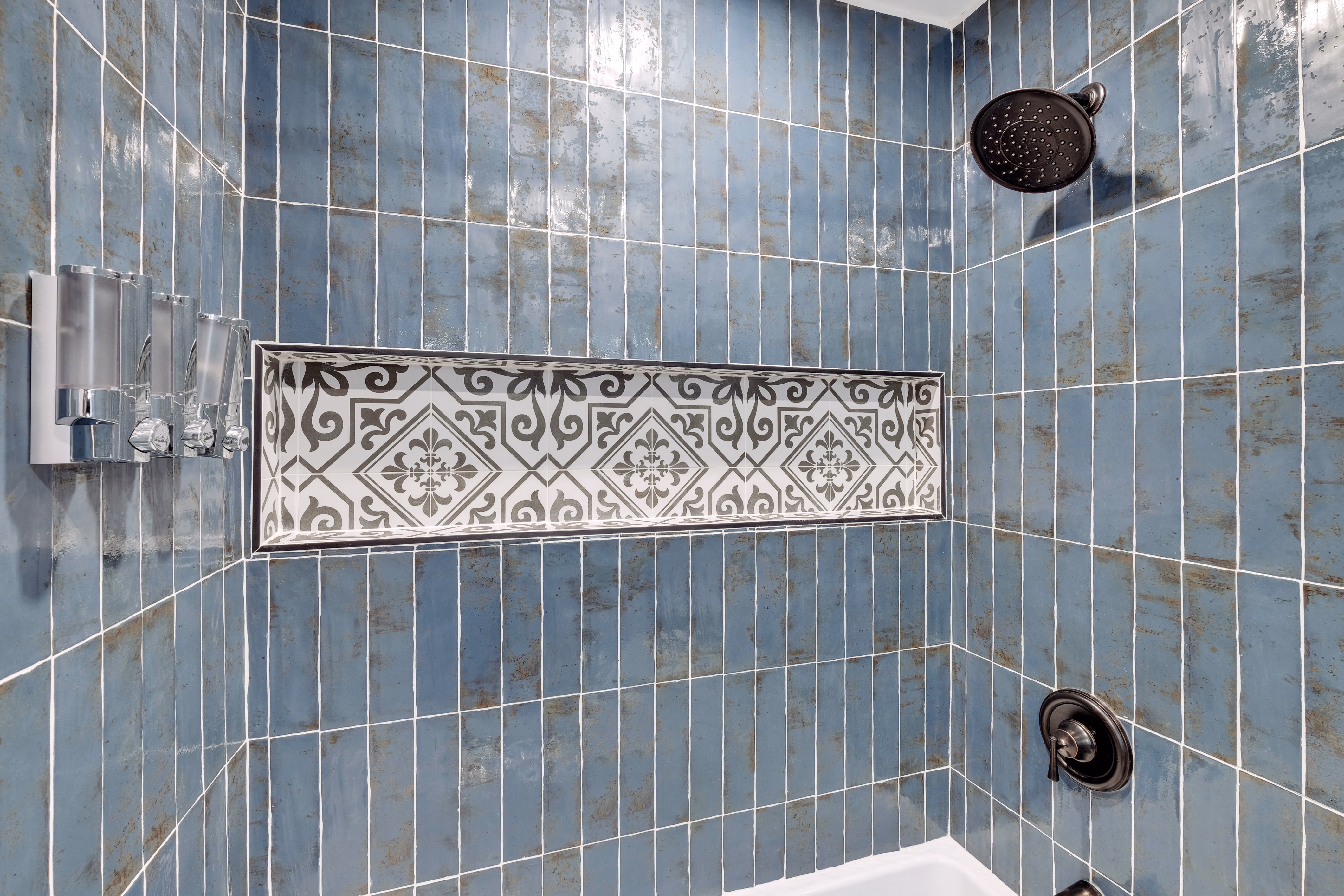 Shower detail — blue tile with patterned accent stripe and black fixtures.