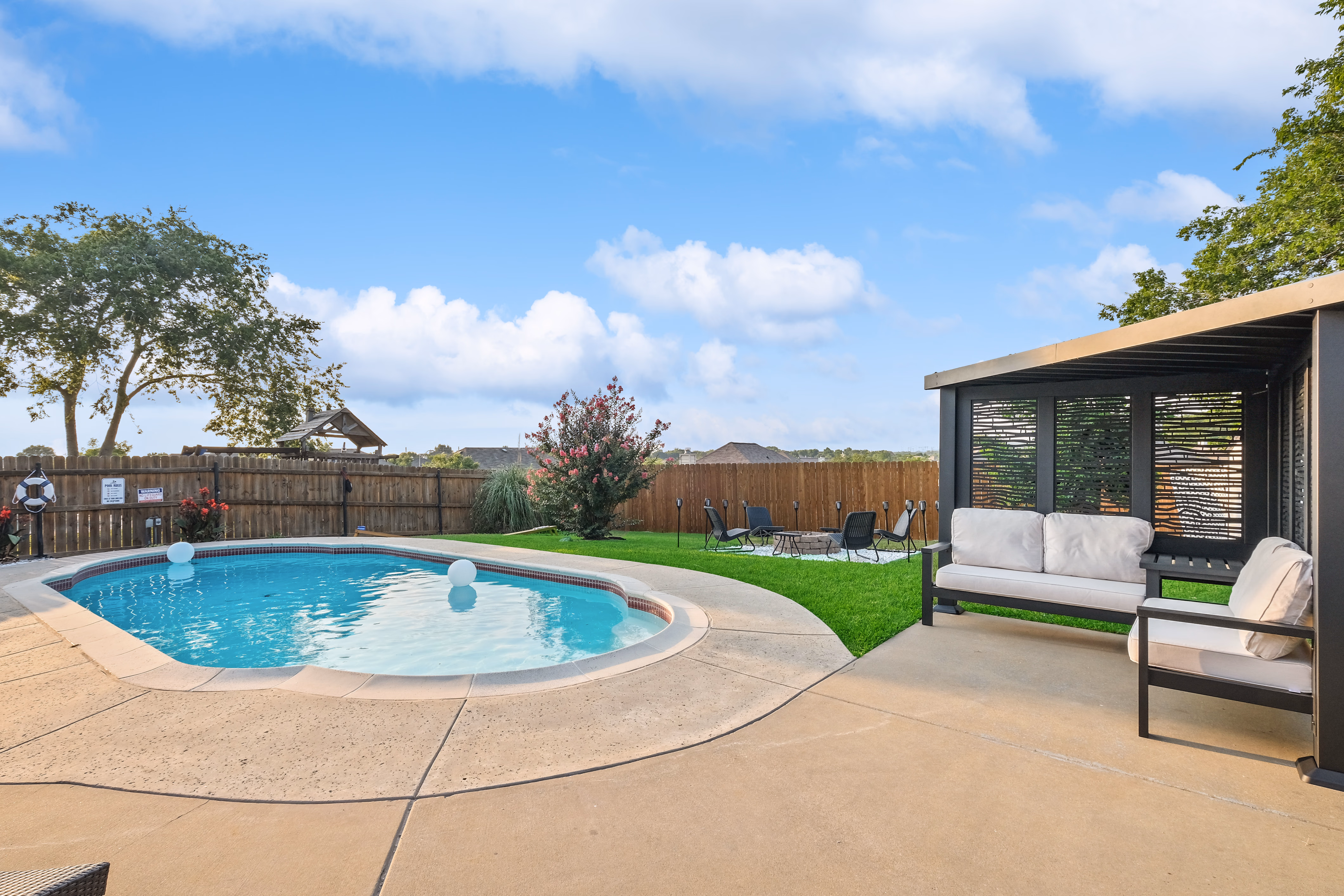 Pool with cabana lounge to right and open lawn view.