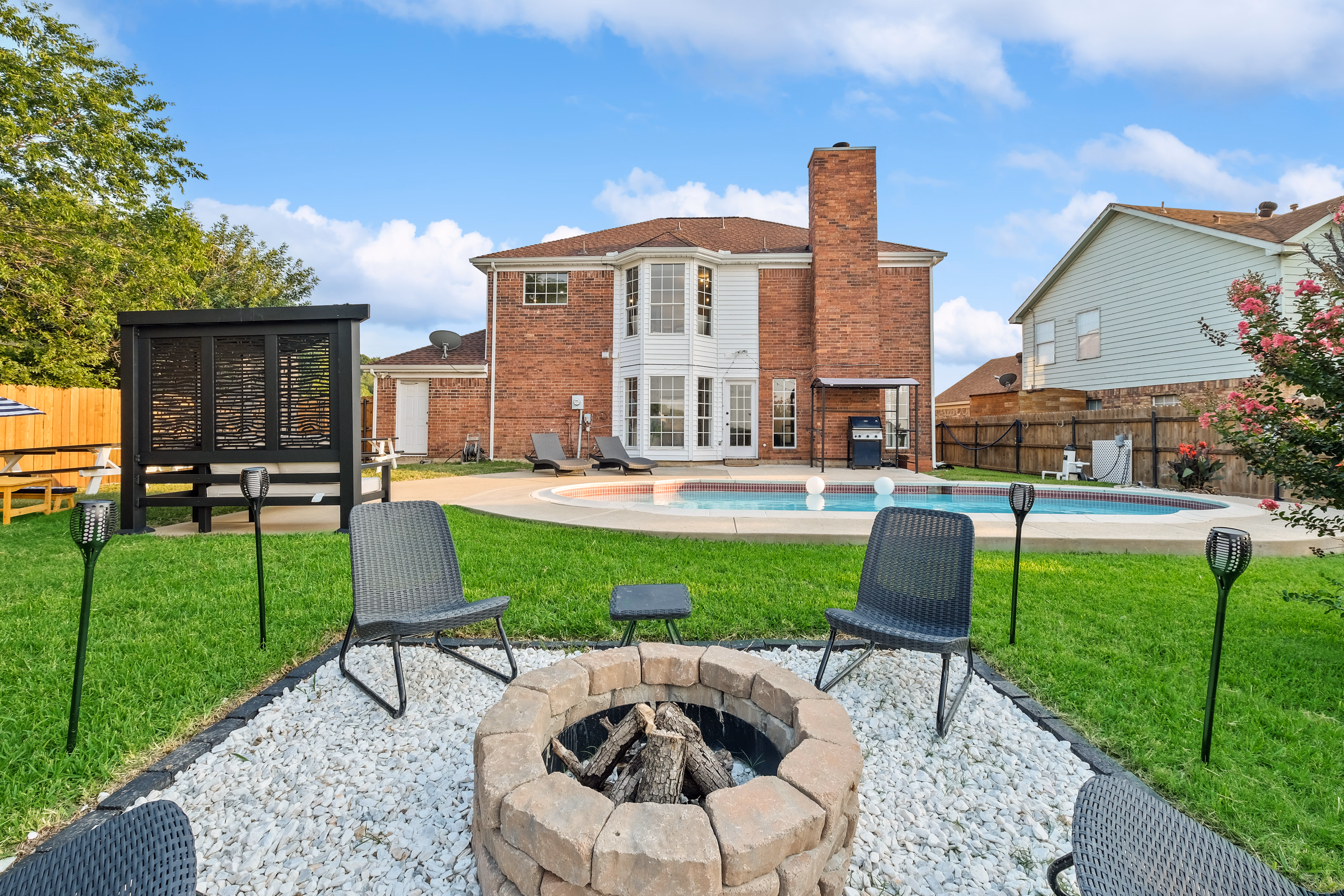 Rear of house from firepit — pool, BBQ, cabana in view.