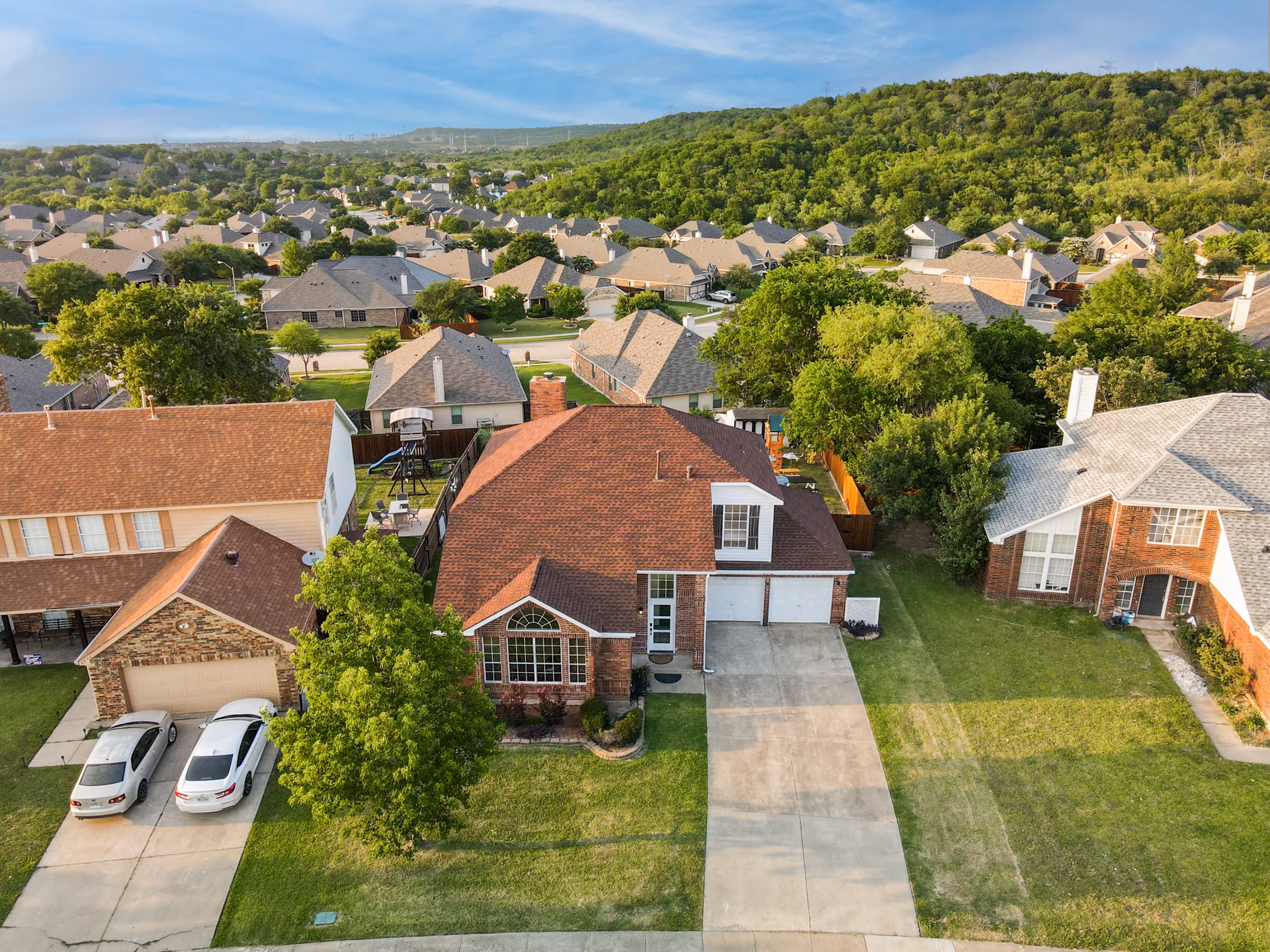Aerial — neighborhood with hills behind, house centered.