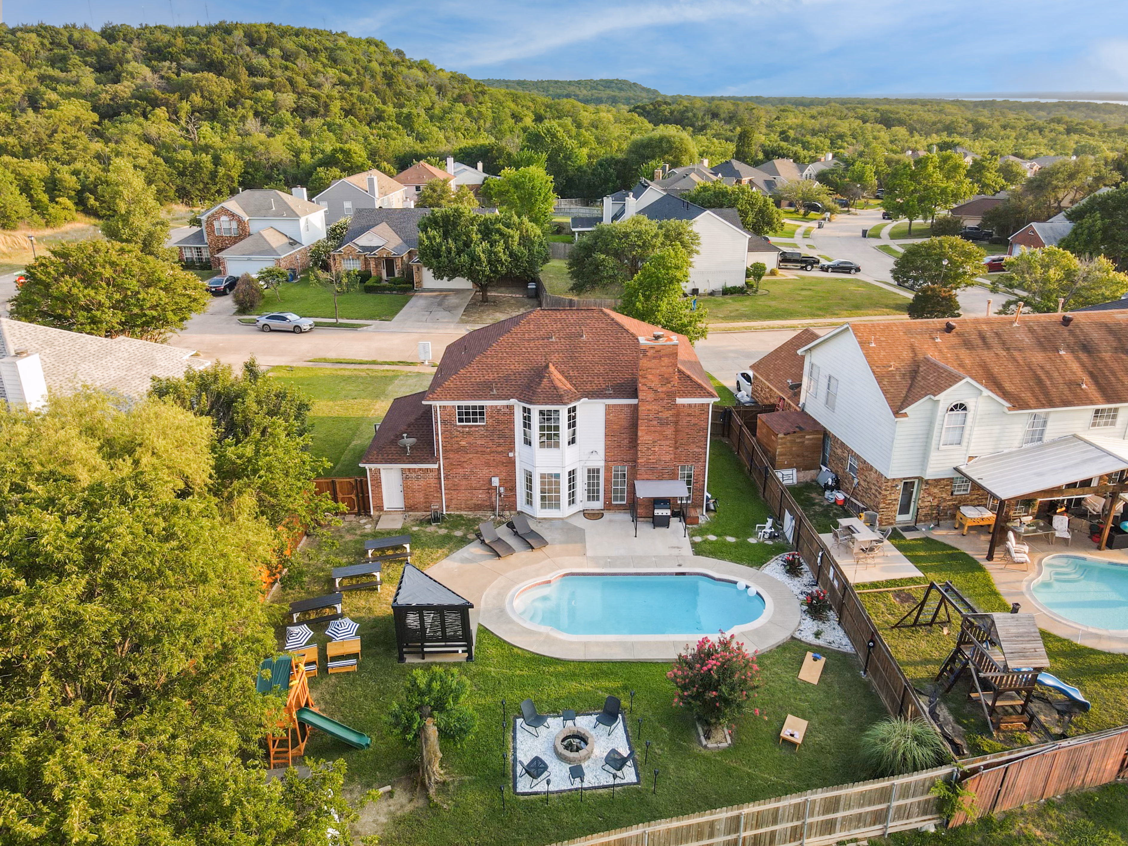Aerial rear — pool, firepit, playset, cabana visible in yard.